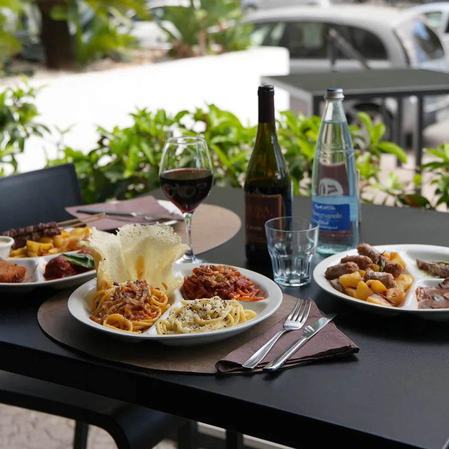 Tavolo apparecchiato della trattoria Magna Roma con primi romani, antipasti e vino